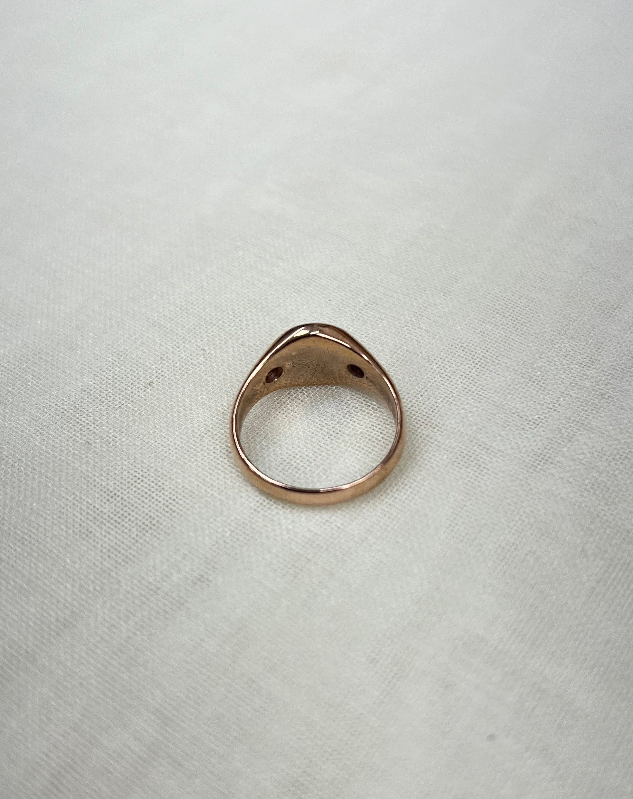 back view of rose gold ring on white fabric background 