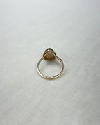 back view of gold ring, on white fabric surface 
