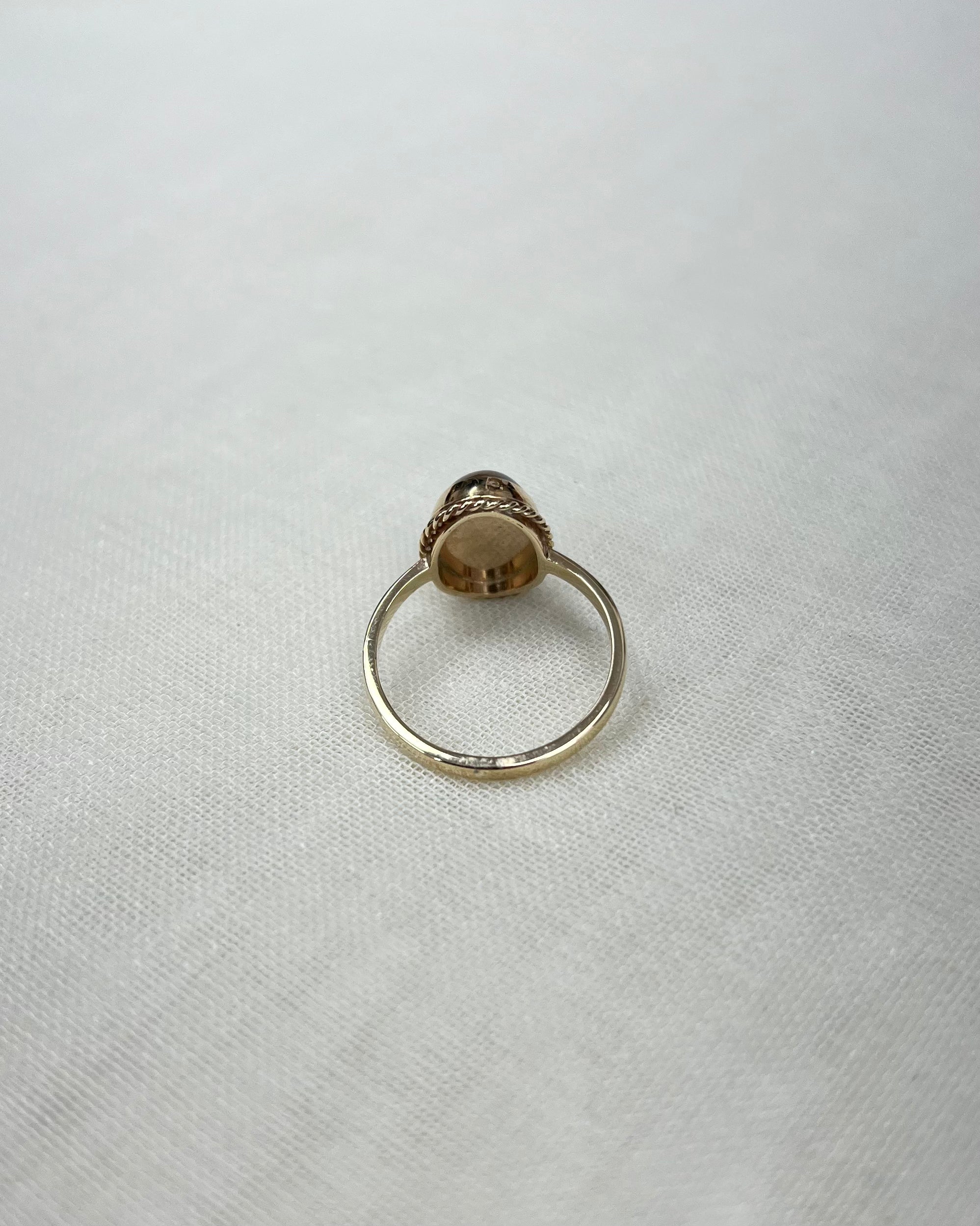 back view of gold ring, on white fabric surface 
