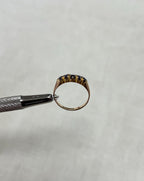 Gold ring being held with a tool on a light beige background
