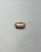 Gold ring with blue stones on a light beige background