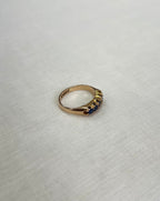 gold ring with blue stones on light beige fabric background 