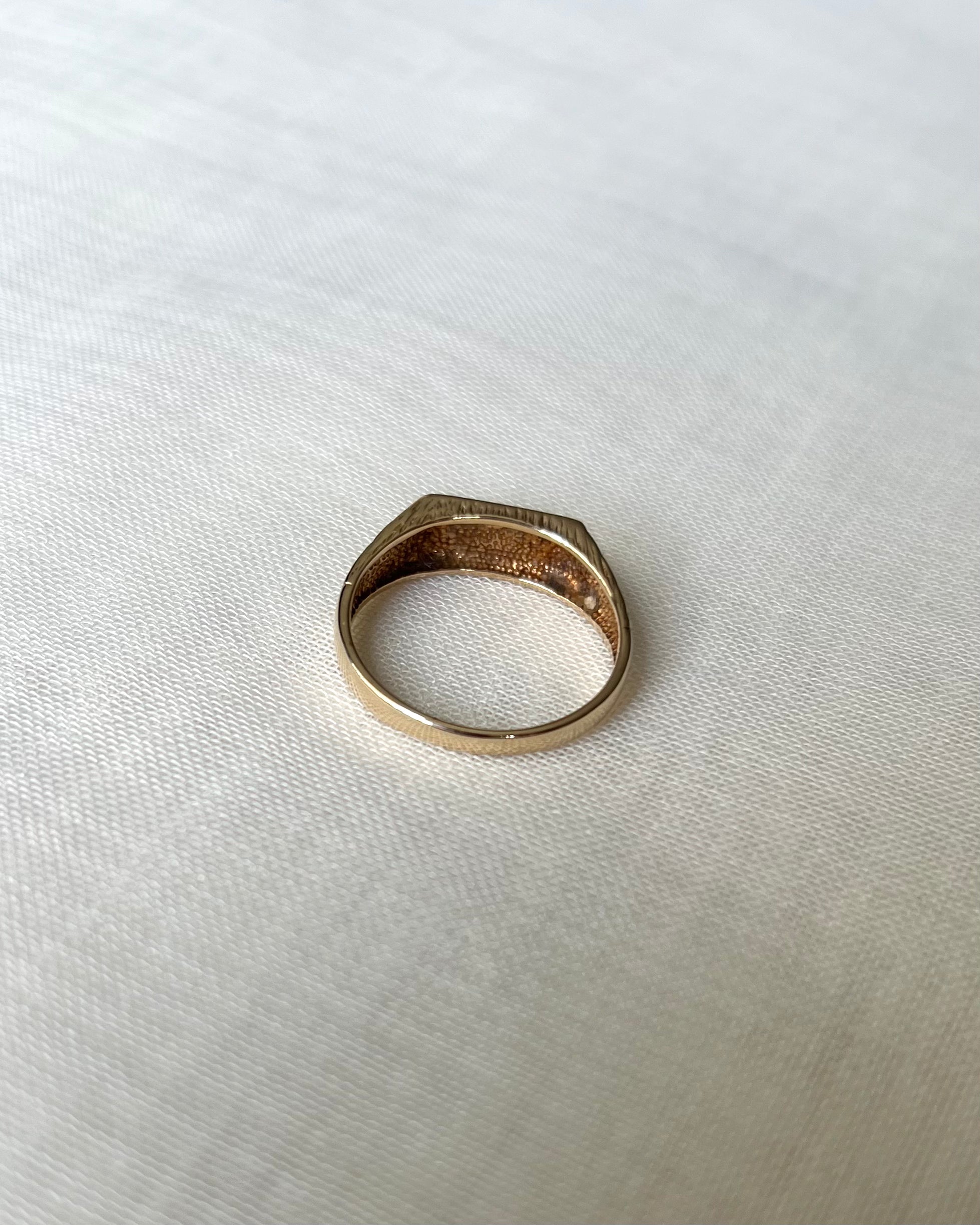 Back view of gold ring, resting on textured white linen background