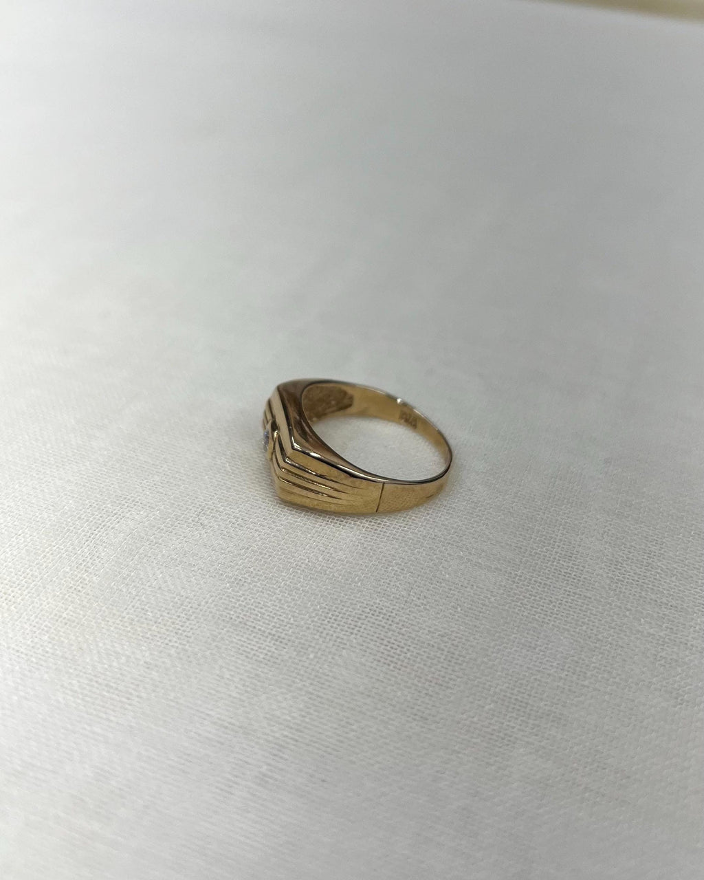 side view of Gold ring on a white fabric background