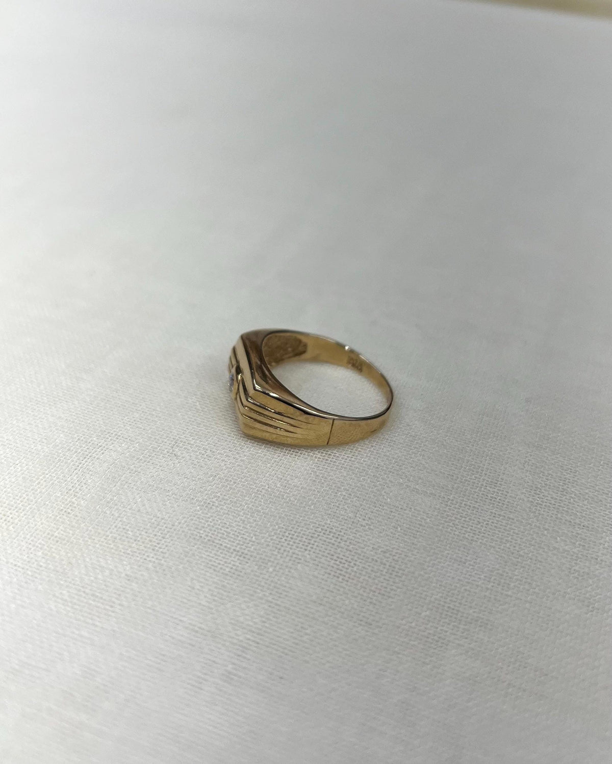 side view of Gold ring on a white fabric background