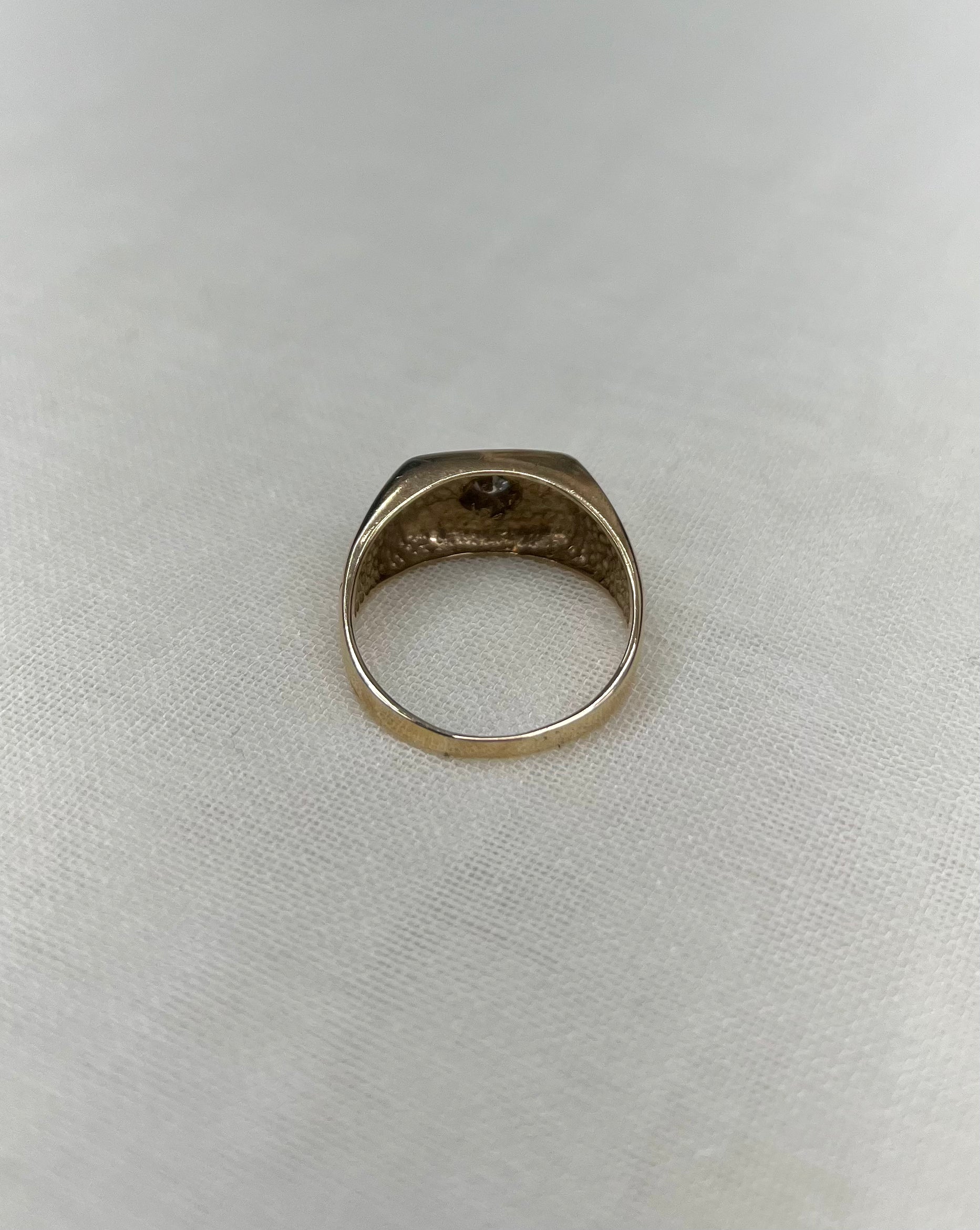 back view of gold ring on white fabric background 