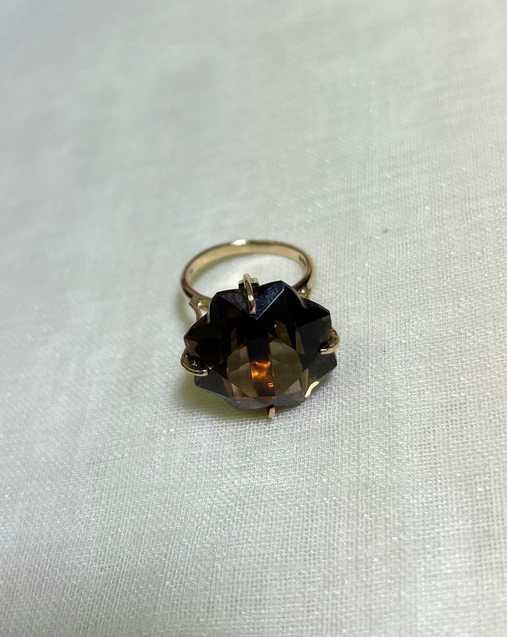 a gold ring with large brown smokey quartz, resting on white background