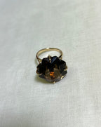 a gold ring with large brown smokey quartz, resting on white background