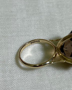 close up of gold ring with visible hallmark with 375 marking, resting on white fabric background 
