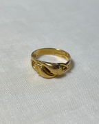 gold ring with two snake heads, resting on white fabric background