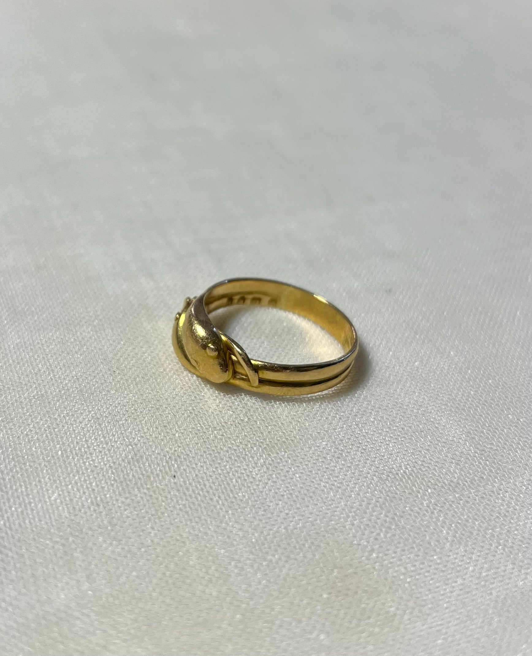 gold snake head ring with double band, resting on white fabric background