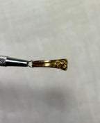 gold snake ring held by silver tool above soft cream background 
