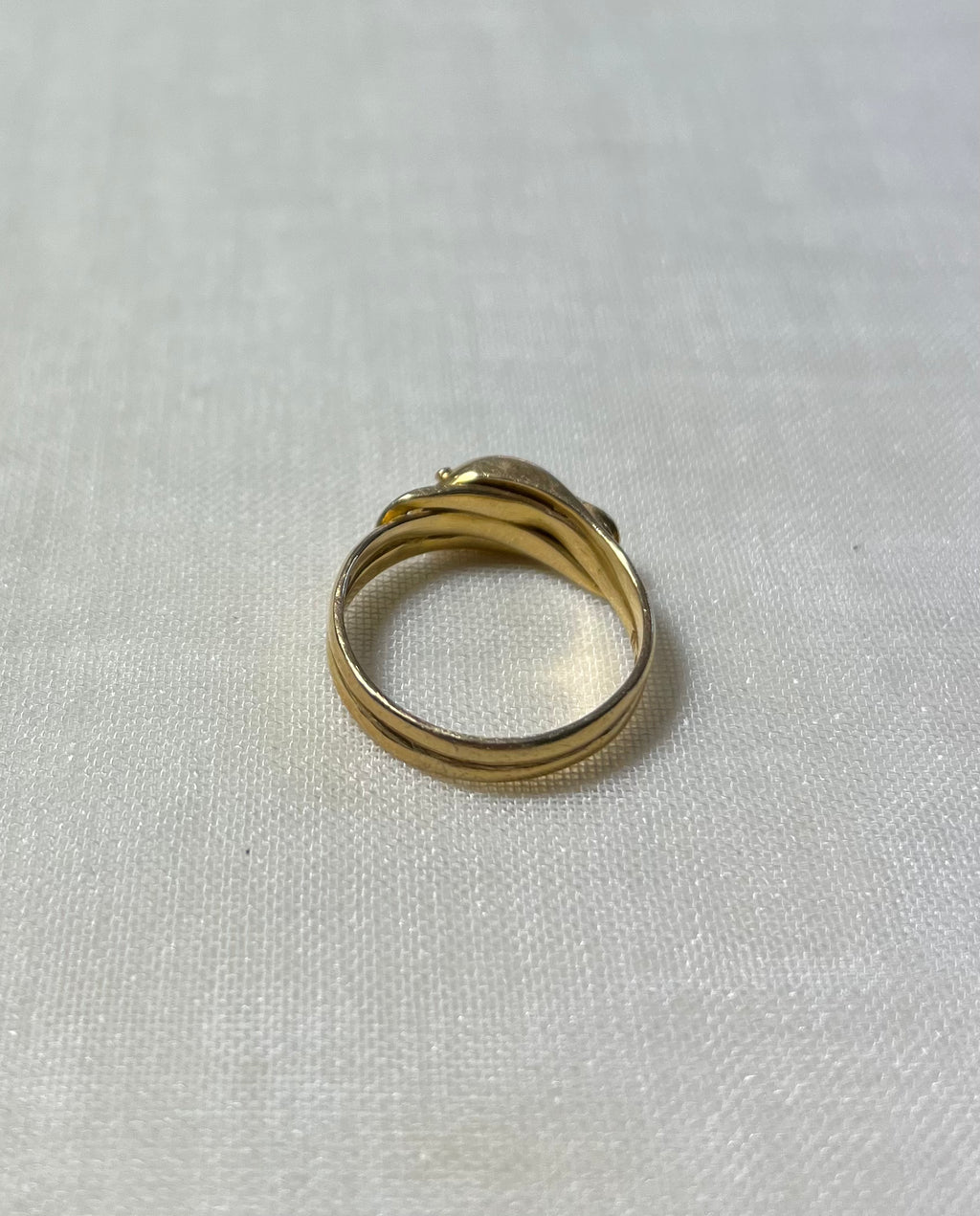 back view of gold double band ring, resting on white fabric background 