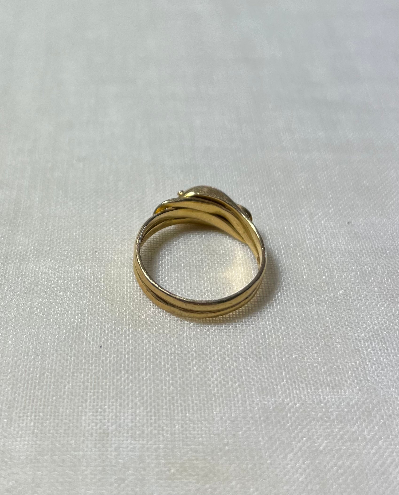 back view of gold double band ring, resting on white fabric background 