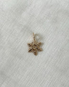 Gold snowflake-shaped pendant on a white fabric background