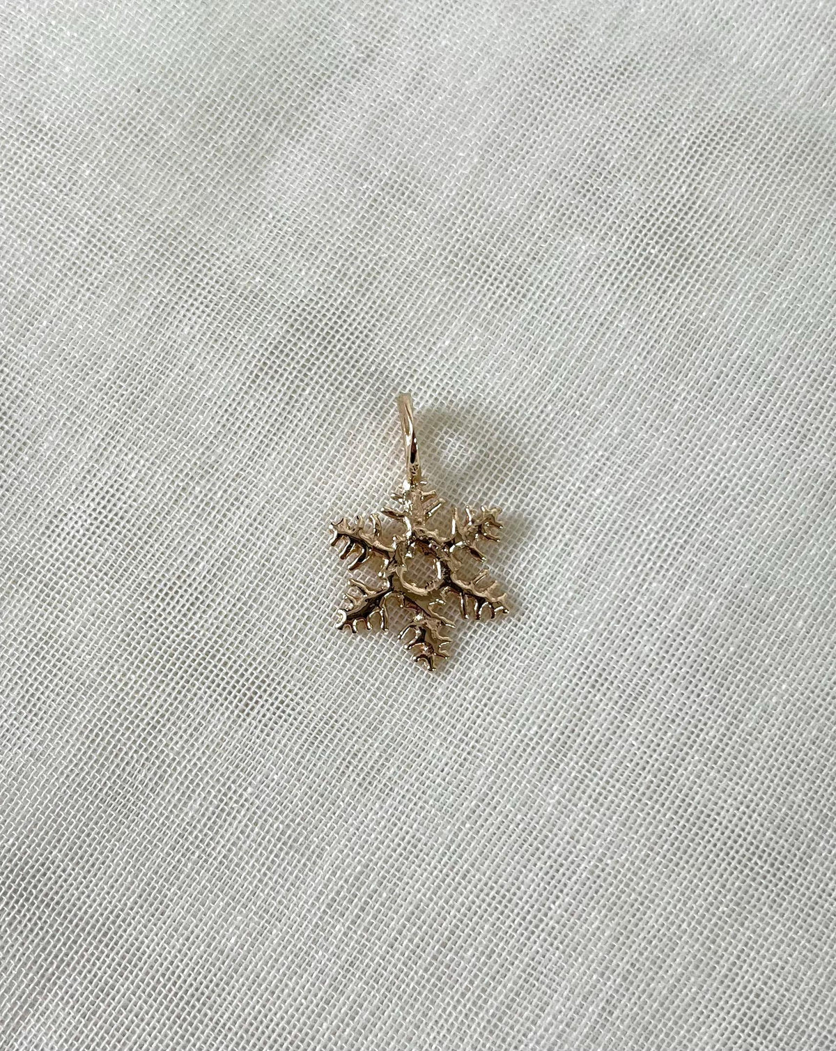 Gold snowflake-shaped pendant on a white fabric background