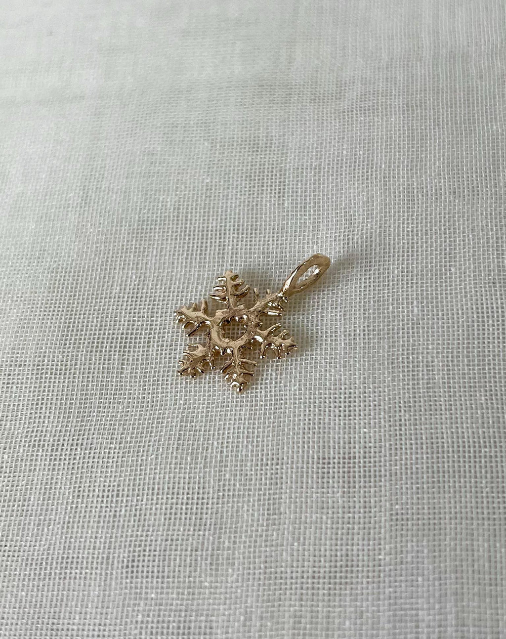 Gold snowflake-shaped pendant on a white fabric background