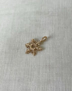 Gold snowflake-shaped pendant on a white fabric background