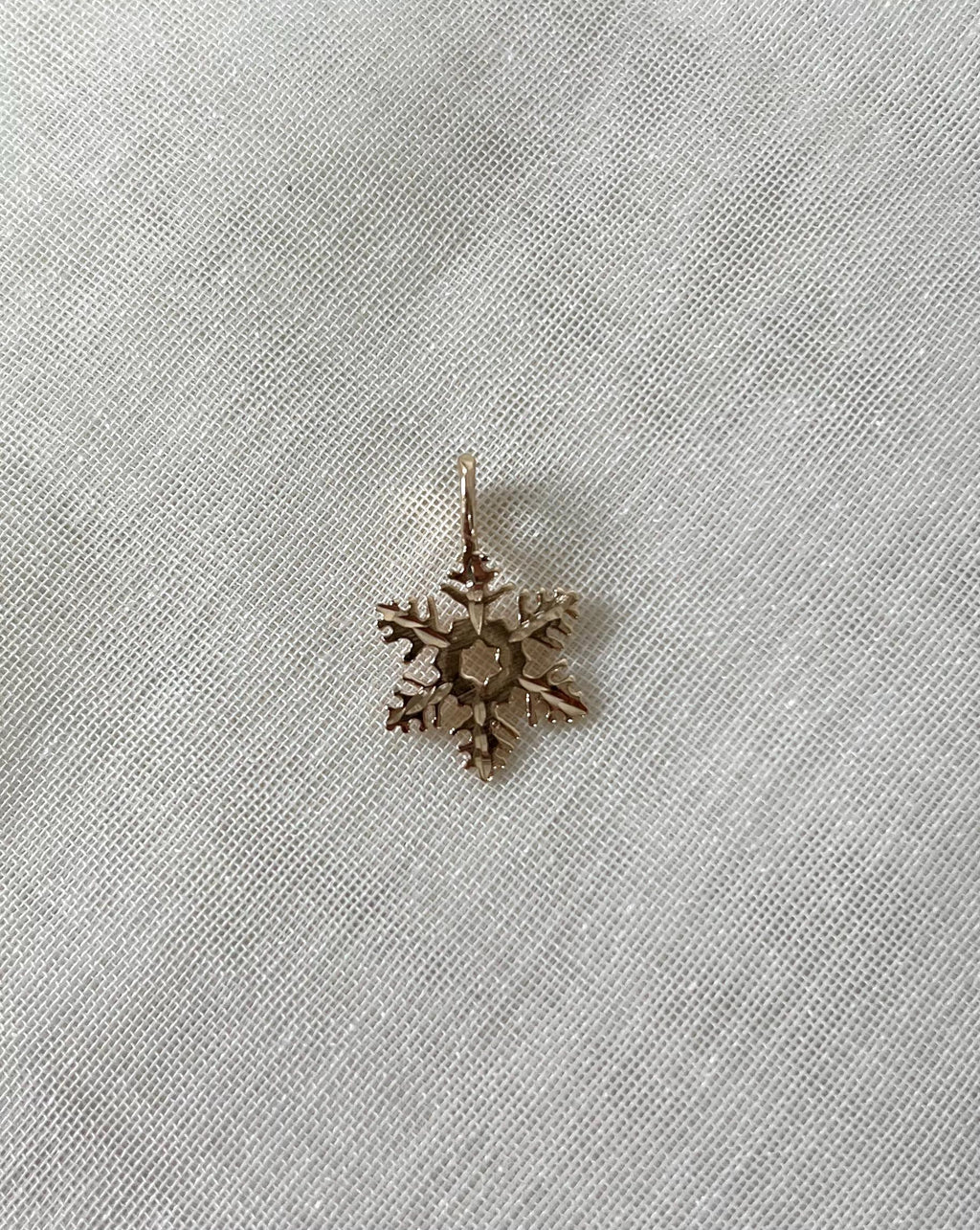 gold snowflake charm on white fabric background 