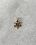 gold snowflake charm on white fabric background 