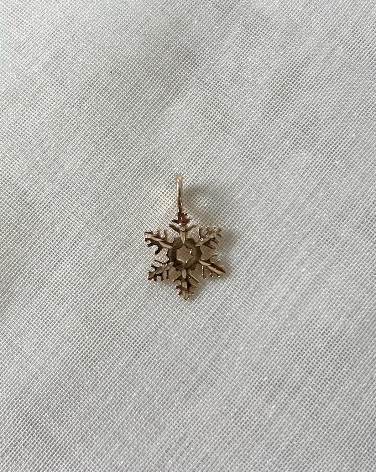 gold snowflake charm on white fabric background 