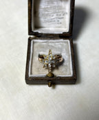 a gold star ring set with diamonds, displayed in brown box on white fabric background