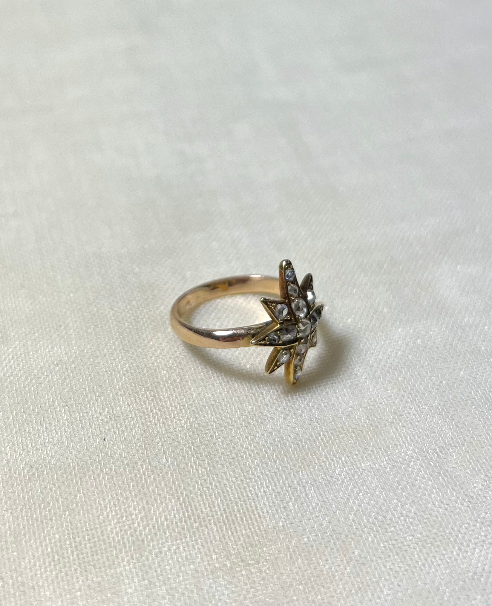 gold star ring set with diamonds on white fabric background 