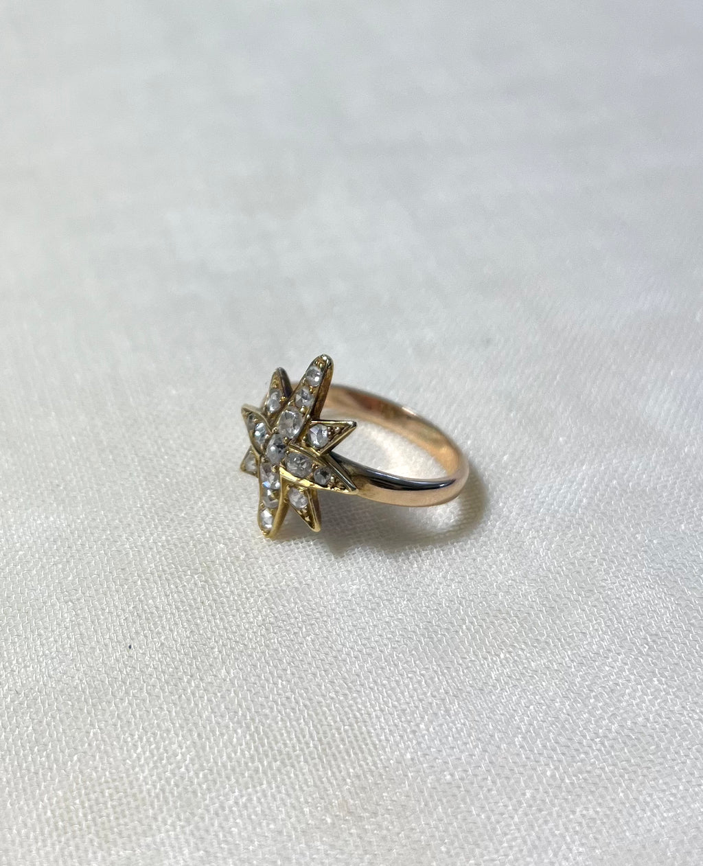 gold star ring set with diamonds on white fabric background