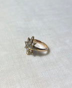 gold star ring set with diamonds on white fabric background