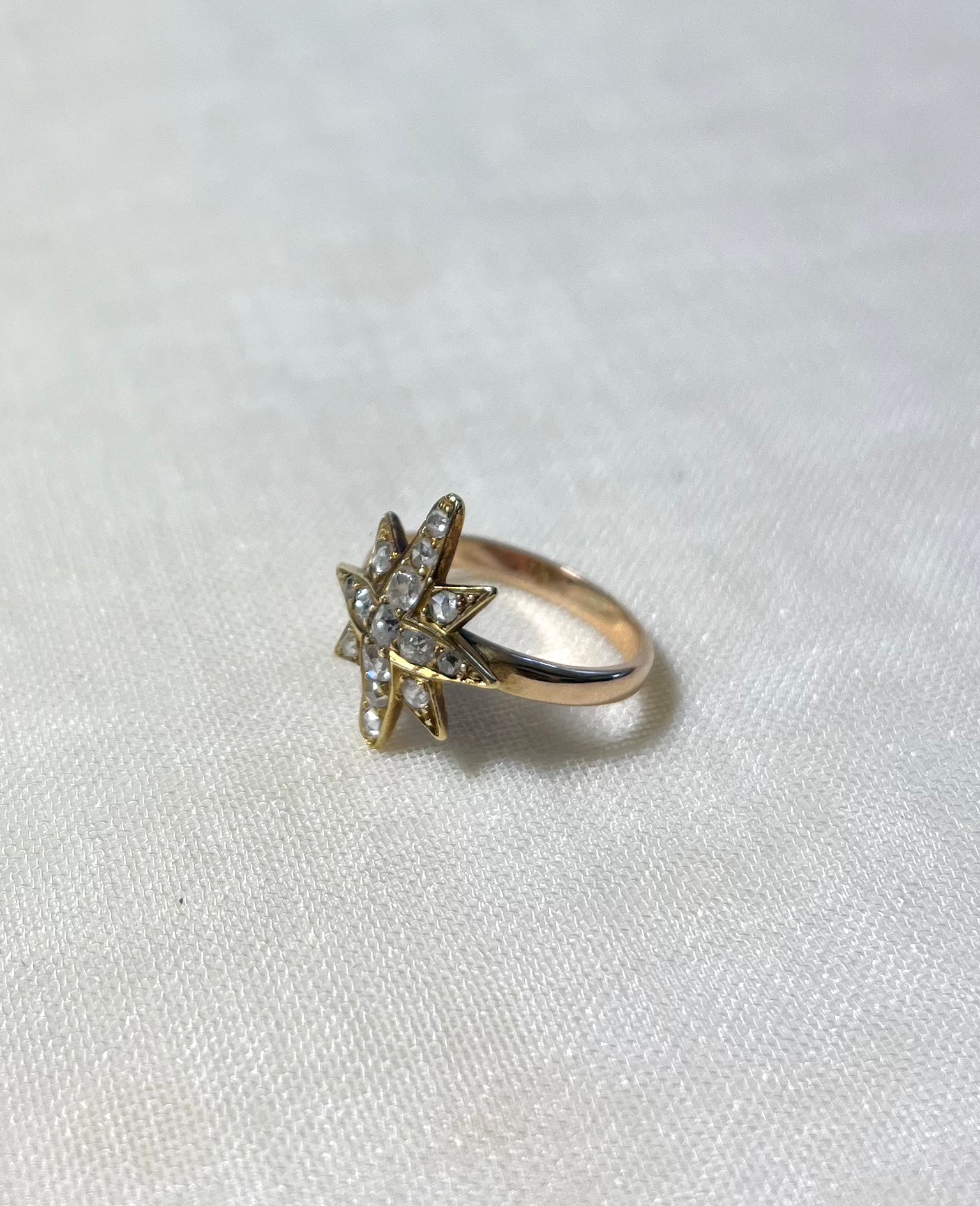 gold star ring set with diamonds on white fabric background