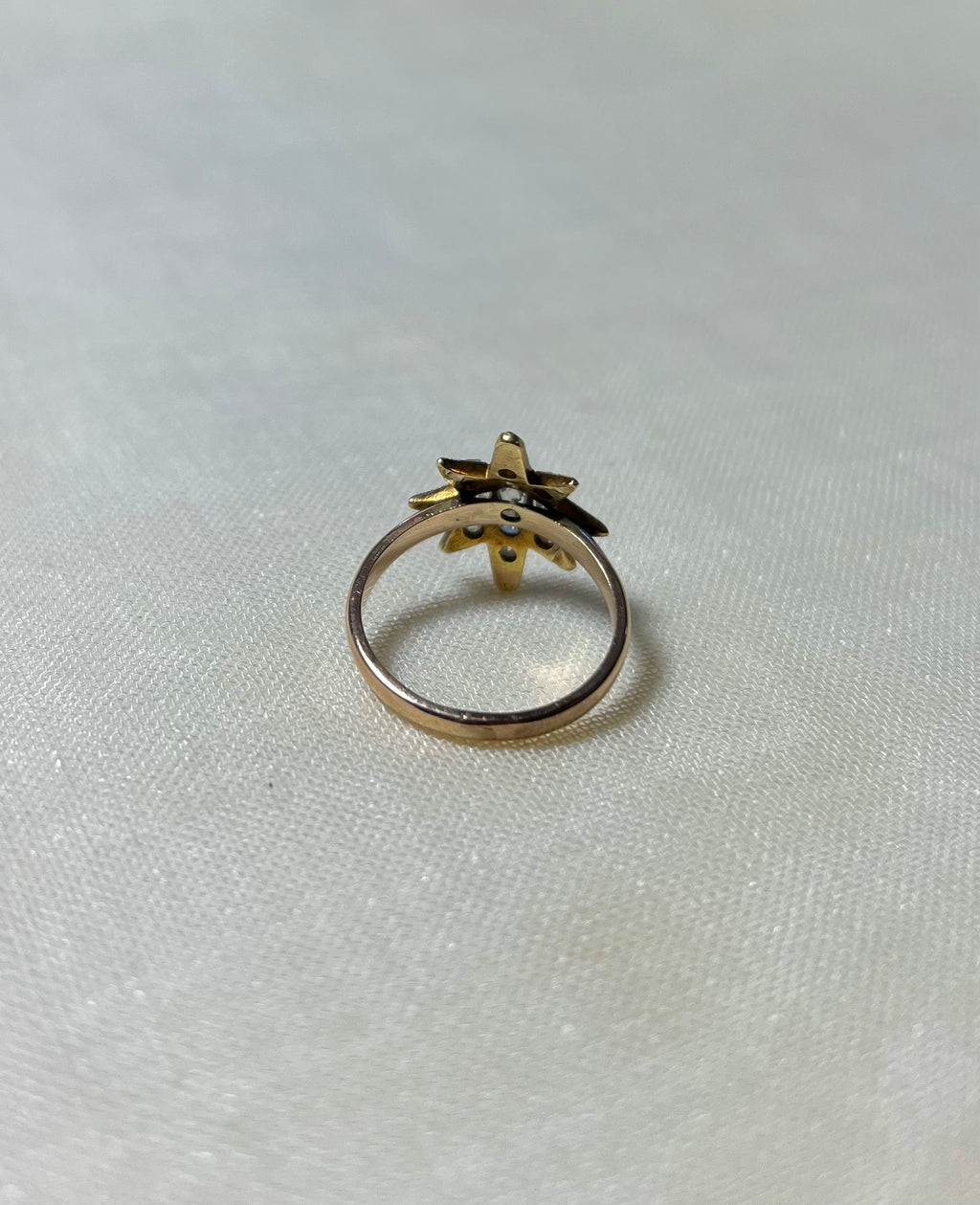 back view of gold star ring on white fabric background 