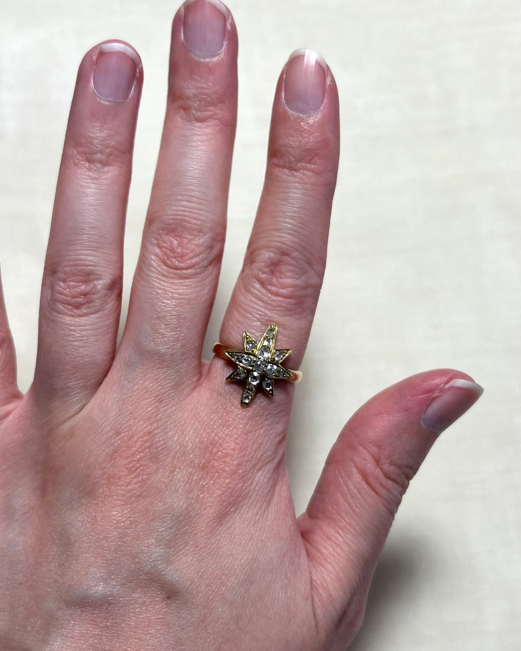 gold star ring set with diamonds worn on hand, white background