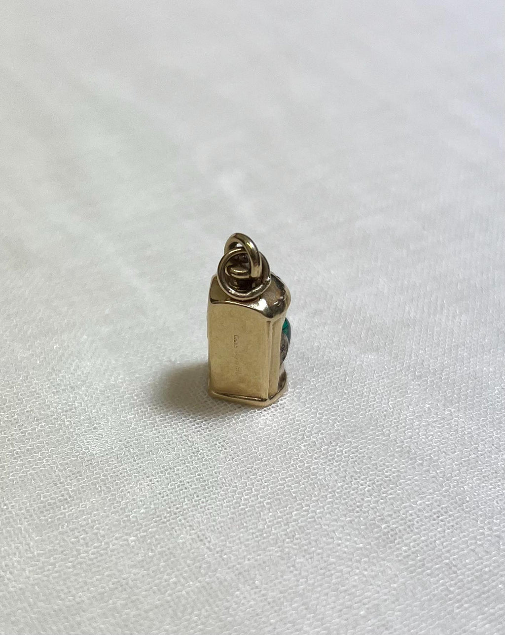 Gold charm on a white fabric background