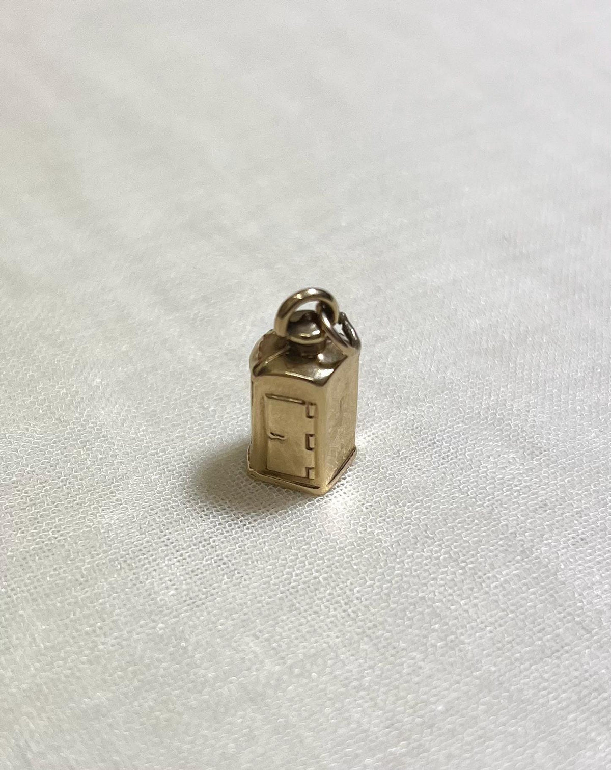 Small gold charm on a white fabric background