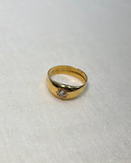 Gold ring with a diamond starburts design on a white fabric background