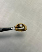 Gold ring with a diamond starburst design held by tweezers on a white background