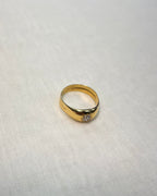A yellow gold ring with a small star-shape and diamond set in the center, resting on a textured off-white fabric background.