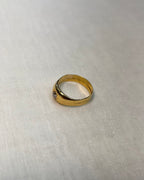 side view of a yellow gold ring with a diamond, photographed on a textured off-white fabric background.
