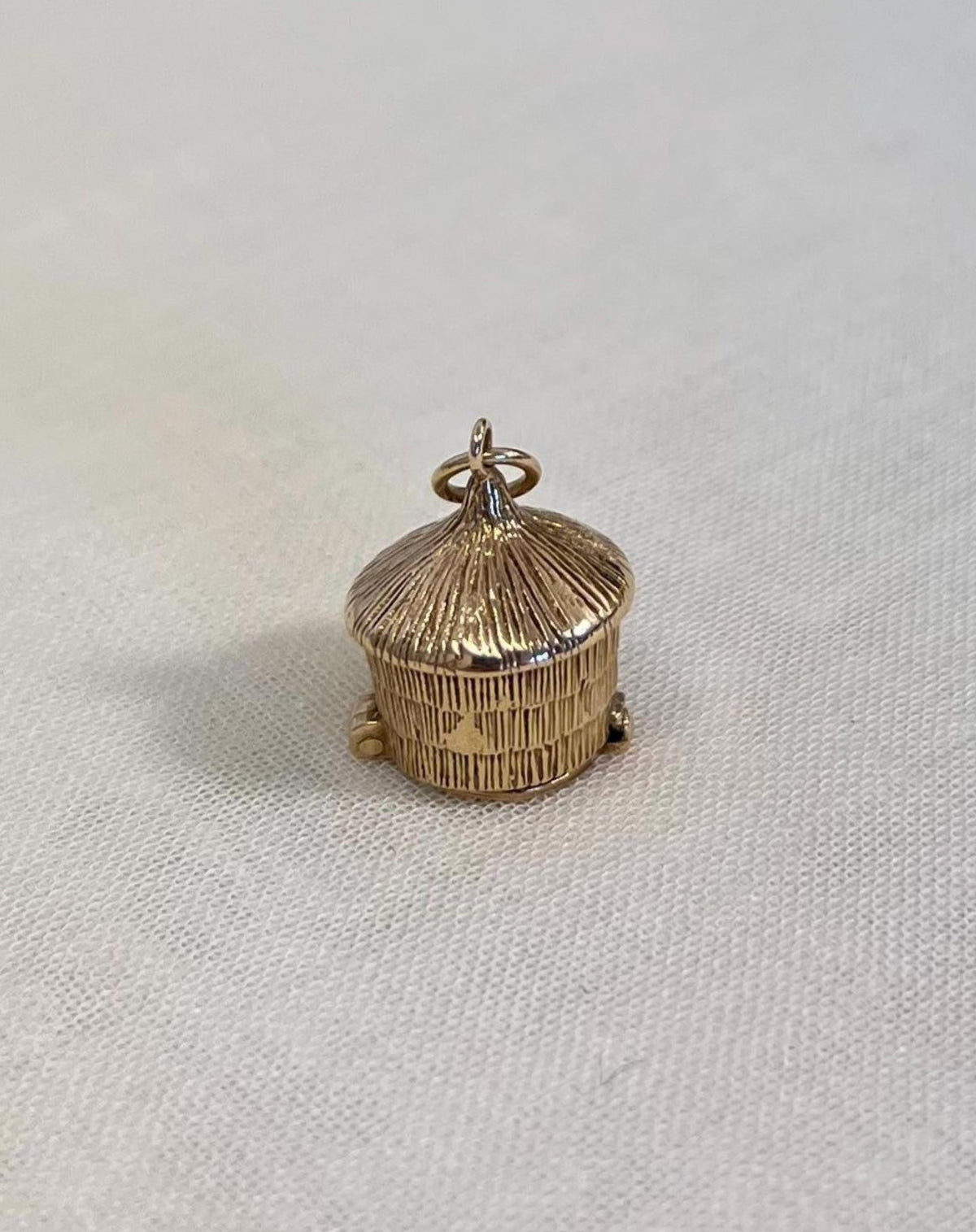 gold textured detail straw hut charm on fabric background