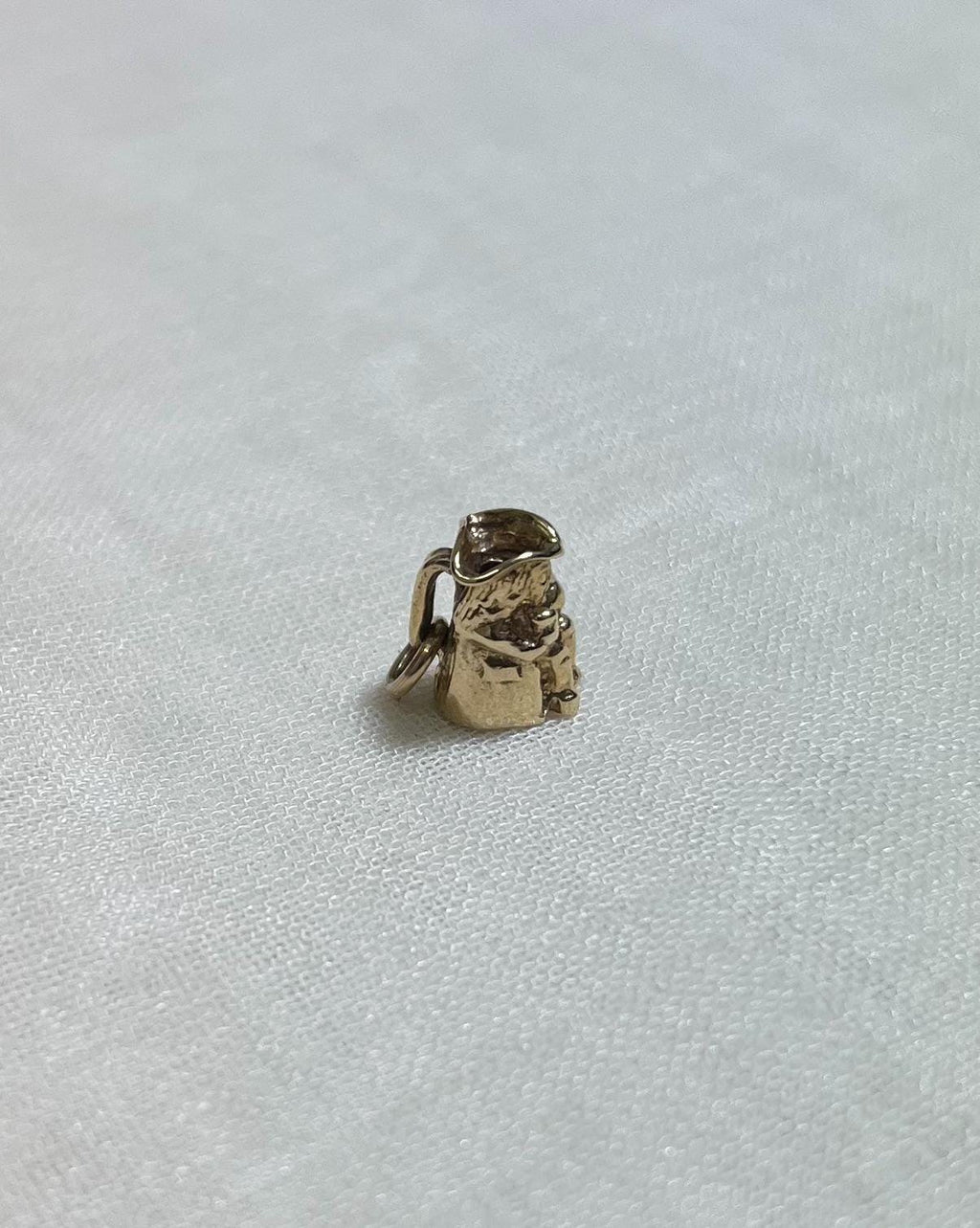small gold toby charm on cream fabric background