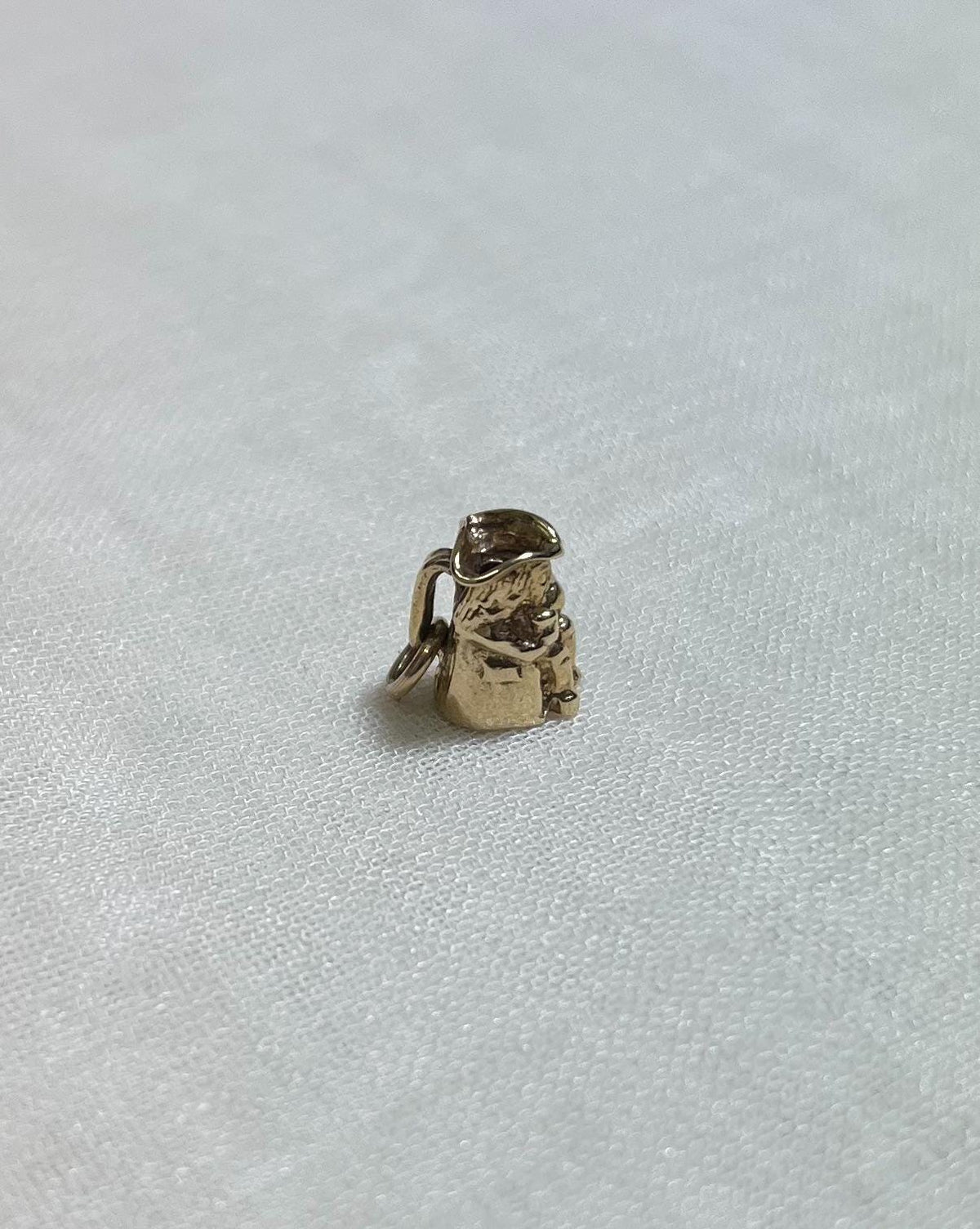 small gold toby charm on cream fabric background