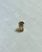 back view of small gold toby jug charm on cream fabric background