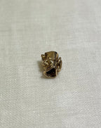 small gold toby jug charm on its side, on cream fabric background