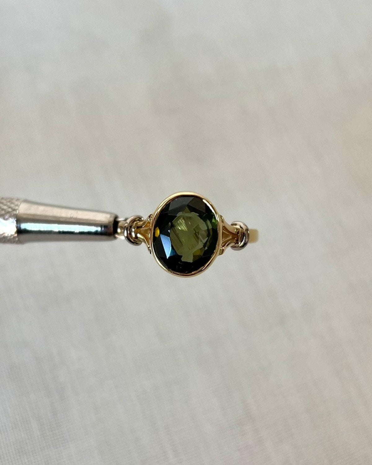 Gold ring with a oval green gemstone on a white background