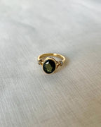 Gold ring with a green gemstone on a light fabric background