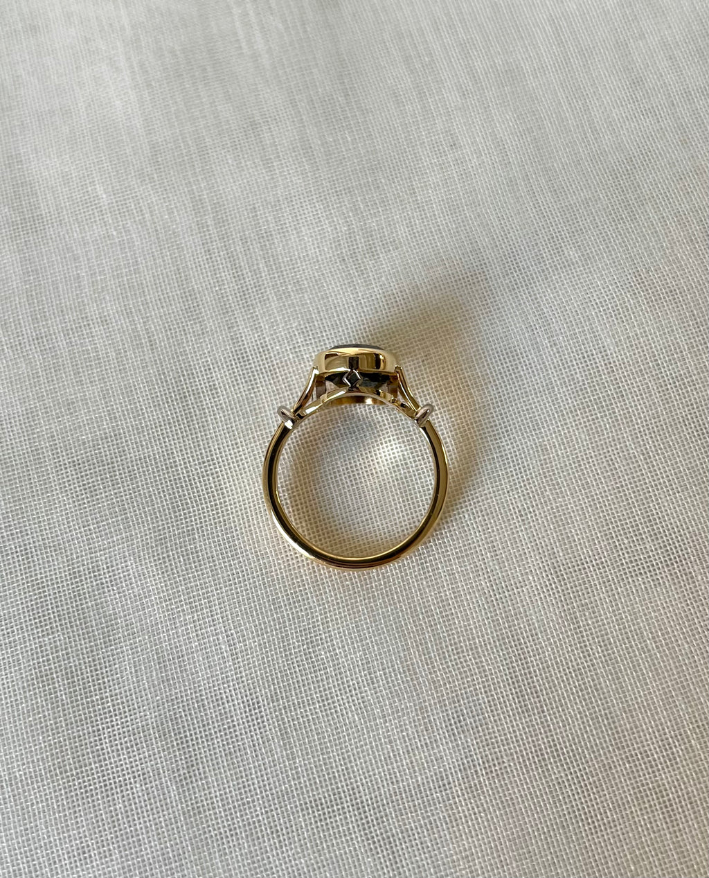 above view of gold ring resting on light beige fabric background 